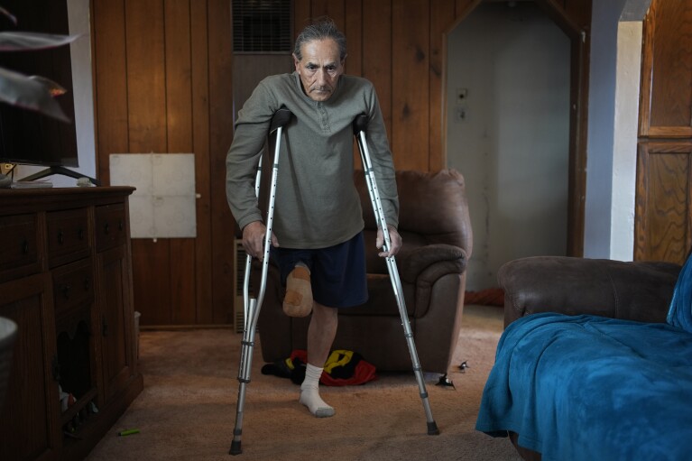 Blas Sanchez makes his way through a room in his home, Jan. 26, 2024, in Winslow, Ariz.  (AP Photo/John Locher)