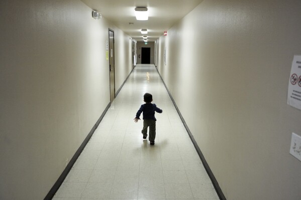 An asylum-seeking boy from Central America runs down a hallway after arriving from an immigration detention center to a shelter in San Diego, Dec. 11, 2018. (AP Photo/Gregory Bull, File)