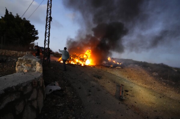 A journalist's car burns after it was hit by Israeli shelling in the Alma al-Shaab border village with Israel, south Lebanon, Friday, Oct. 13, 2023. An Israeli shell landed in a gathering of international journalists covering clashes on the border in south Lebanon, killing one and leaving six others injured. (AP Photo/Hassan Ammar)
