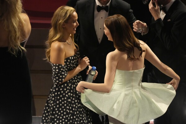 Jennifer Lawrence, left, and Emma Stone speak during the Oscars on Sunday, March 10, 2024, at the Dolby Theatre in Los Angeles. (AP Photo/Chris Pizzello)