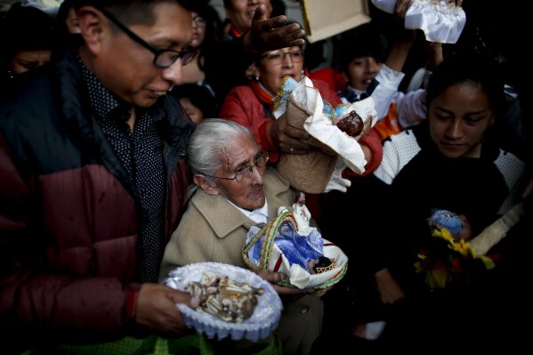 In this picture taken Monday, Jan. 6, 2020, people wait their turn to have their baby Jesus dolls blessed by a priest as they leave the Three Kings Day Mass at San Francisco Church in La Paz, Bolivia. Outside the church, many parishioners went to indigenous guides to get additional blessings that come from the country's belief in the Pachamama, or mother earth deity. (AP Photo/Natacha Pisarenko)