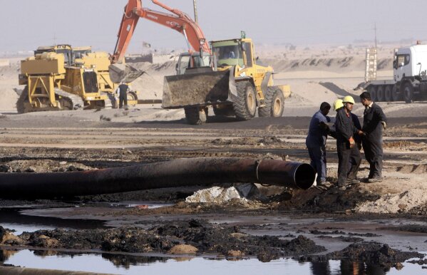 FILE - In this Dec. 14, 2011 file photo, workers repair oil pipelines at Rumaila oil fields, near the southern Iraqi city of Basra. Iraq is rich in oil, but protesters say they don’t see the fruits of this wealth. Fueling the unrest, which began on Oct. 1, 2019, is anger over an economy flush with oil money that has failed to bring jobs or improvements to the lives of young people, who are the majority of those taking to the streets. (AP Photo/Nabil al-Jurani, File)