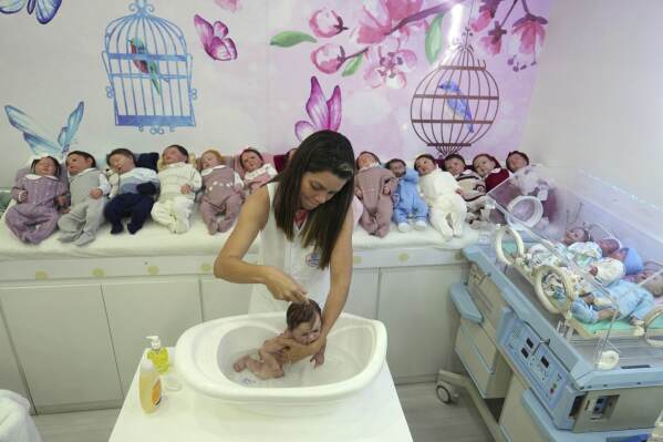 An employee bathes a hyper-realistic reborn babydoll at a shopping mall in Campinas, Brazil, Saturday, May 24, 2025. (AP Photo/Andre Penner)