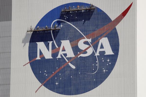 FILE - Workers on scaffolding repaint the NASA logo near the top of the Vehicle Assembly Building at the Kennedy Space Center in Cape Canaveral, Fla., May 20, 2020. (AP Photo/John Raoux, File)