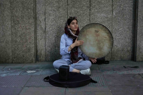 A street musician plays the Daf, a hand-held Persian drum, on a sidewalk in northern Tehran, Iran, Monday, June 2, 2025. (AP Photo/Vahid Salemi)