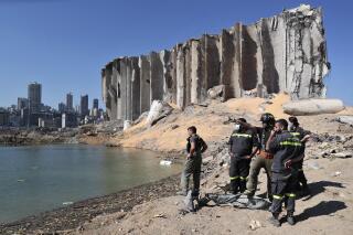 FILE - A rescue team surveys the site of a massive explosion in the port of Beirut, Lebanon, Aug. 7, 2020. A Lebanese court Tuesday, Dec. 7, 2021, cleared the way for the judge leading the state's investigation into last year’s massive explosion at Beirut’s port to resume his work. The probe was suspended for more than a month following legal challenges from former officials charged in the case. (AP Photo/Thibault Camus, File)