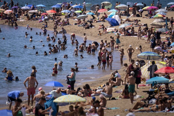 Bathers cool off in the water while others sunbathe on a Barcelona beach, Spain, Wednesday, July 24, 2024. (AP Photo/Emilio Morenatti,File)