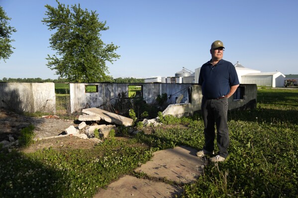 West Alton Mayor Willie Richter poses for a photo outside what remains of a flood-damaged and burned home Wednesday, May 22, 2024, in West Alton, Mo. Vacant properties invite arson, said Richter, who said four or five abandoned homes have burned since the last big flood. (AP Photo/Jeff Roberson)