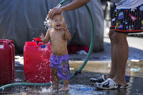 A man pours water on his daughter on a hot summer day in Manila, Philippines on Friday, April 26, 2024. (Ǻ Photo/Aaron Favila)
