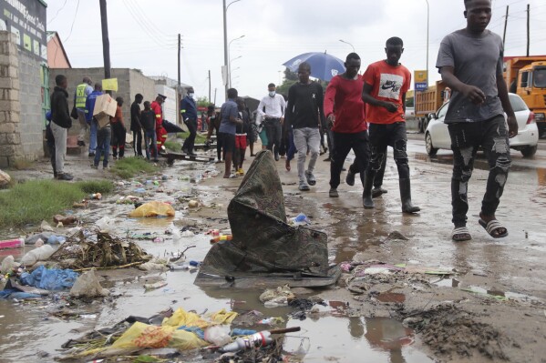 People walk down a water-logged road in Lusaka, Zambia, Friday, Jan 12, 2024. The country is reeling from a major cholera outbreak that has killed more than 400 people and infected more than 10,000, leading authorities to order schools across the country to remain shut after the end-of-year holidays. (AP Photo)