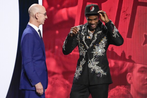 Scoot Henderson, right, dons a Portland Trailblazers hat with NBA Commissioner Adam Silver watching after being selected third overall by the Trail Blazers during the NBA basketball draft Thursday, June 22, 2023, in New York. (AP Photo/John Minchillo)