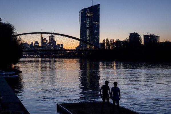Two boys stand at the river Main near the European Central Bank in Frankfurt, Germany, after sunset on Friday, Sept. 8, 2023. (AP Photo/Michael Probst)