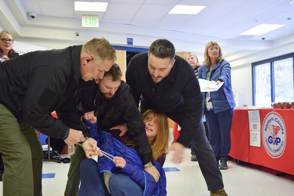 Employees of a security firm, LEAR Asset Management, drag Post Falls resident Teresa Borrenpohl out of a town hall meeting on Saturday, Feb. 22, 2025, in Post Falls, Idaho. (Hailey Hill/Coeur D'Alene Press via AP)