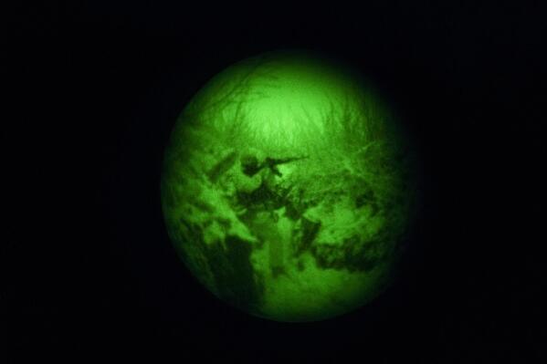 Seen through a night-vision device, a Ukrainian serviceman aims his weapon while patrolling positions on a frontline outside Avdiivka, Donetsk region, eastern Ukraine, Friday, Feb. 4, 2022. The U.S. accused the Kremlin of an elaborate plot to fabricate an attack by Ukrainian forces that Russia could use as a pretext to take military action against its neighbor. (AP Photo/Vadim Ghirda)