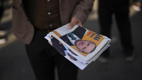 A supporter of Turkish President and People's Alliance's presidential candidate Recep Tayyip Erdogan gives handouts to commuters in Istanbul, Turkey, Tuesday, May 23, 2023. Turkish President Recep Tayyip Erdogan is favored to win reelection in a presidential runoff Sunday, May 28, 2023, despite a host of domestic issues. (AP Photo/Francisco Seco)