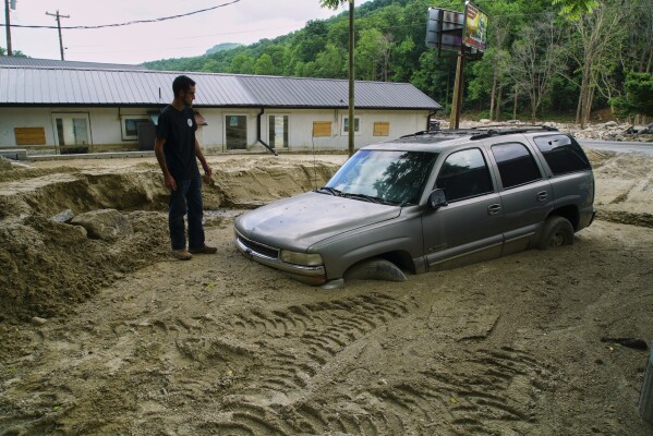 Jonathan Graef stands beside a worker's car engulfed by a slide at his family's Best View Inn in Chimney Rock Village, N.C., on Wednesday, May 14, 2025. He and his siblings were renovating when Hurricane Helene struck and the inn has flooded twice more since. (AP Photo/Allen G. Breed)