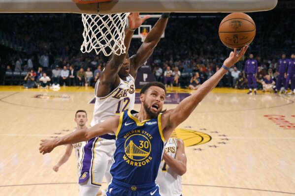 Golden State Warriors guard Stephen Curry, front, shoots as Los Angeles Lakers forward Devontae Cacok defends during the first half of a preseason NBA basketball game Monday, Oct. 14, 2019, in Los Angeles. (AP Photo/Mark J. Terrill)