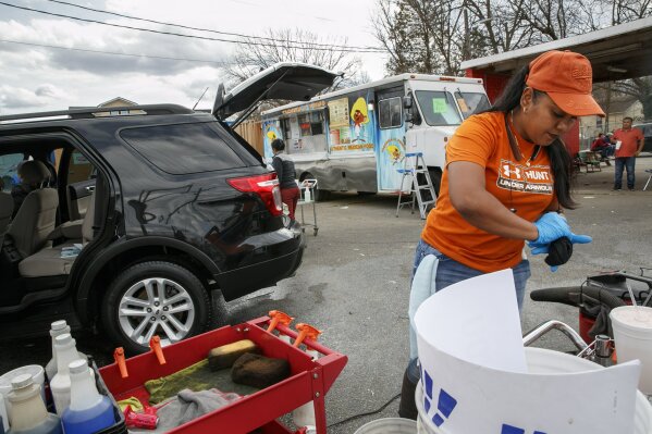 Esperanza Carrillo, of Burlington, N.C., washes cars at Vivas Hand Car Wash, Wednesday, March 11, 2020, along a strip of Latino owned businesses. (AP Photo/Jacquelyn Martin)