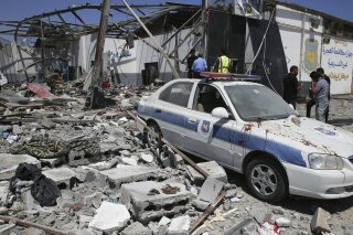 FILE - In this July 3, 2019, file photo, debris covers the ground and an emergency vehicle after an airstrike at a detention center in Tajoura, east of Tripoli in Libya. The government of Libya’s Prime Minister Fayez Sarraj has been battling for months to keep control of the capital of Tripoli amid an offensive by forces aligned with a rival authority based in the country’s eastern portion. (AP Photo/Hazem Ahmed, File)