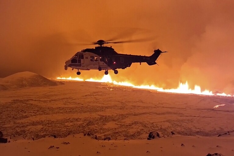 This image made from video provided by the Icelandic Coast Guard shows its helicopter flying near magma running on a hill near Grindavik on Iceland's Reykjanes Peninsula sometime around late Monday, Dec. 18, or early Tuesday, Dec. 19, 2023. A volcanic eruption started Monday night on Iceland's Reykjanes Peninsula, turning the sky orange and prompting the country's civil defense to be on high alert. (Icelandic coast guard via AP)