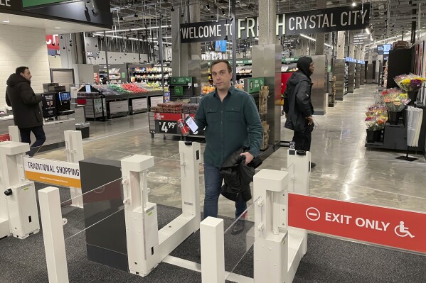 Stuart Dryden leaves a grocery store on Wednesday, Feb. 21, 2024, in Arlington, Va. Dryden is aware of big price disparities between branded products and their store-label competitors, which he now favors. (AP Photo/Chris Rugaber)