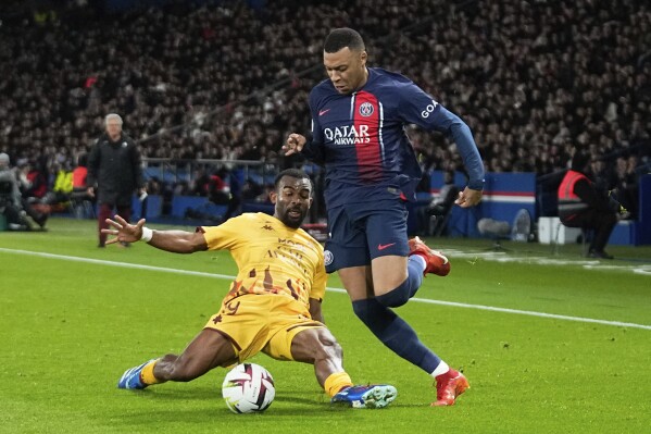 PSG's Kylian Mbappe, right, challenges for the ball with Metz's Habib Maiga, during the French League One soccer match between Paris Saint-Germain and Metz at the Parc des Princes in Paris, Wednesday, Dec 20, 2023. (AP Photo/Michel Euler)