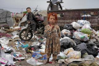 Dos niños parados entre basura junto a su casa en Kabul, Afganistán, el lunes 18 de abril de 2022. (AP Foto/Ebrahim Noroozi, Archivo)