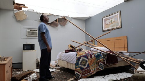 With the roof blown off by severe winds, Brian Patel, owner of the Skyline Motel in the suburban town of McCook, Ill., for the past 30 years, surveys storm damage in one of the motel rooms, Thursday, July 13, 2023. (Antonio Perez/Chicago Tribune via AP)