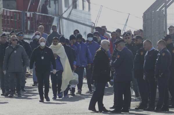 Migrants follow the authorities after their arrival, as Italy sent 49 people to Albania for processing following earlier court rejections to Albania, in Shengjin, northwestern Albania, Tuesday, Jan. 28, 2025. (AP Photo/Vlasov Sulaj)