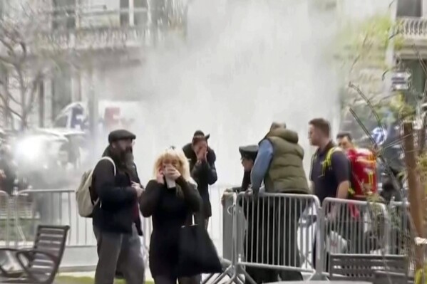 In this image taken from video, bystanders react after witnessing a man who lit himself on fire was extinguished, Friday, April 19, 2024, in a park outside Manhattan criminal court in New York. Emergency crews rushed away a person on a stretcher after the fire was extinguished outside the courthouse where jury selection was taking place in former President Donald Trump's hush money criminal case. (AP Photo)