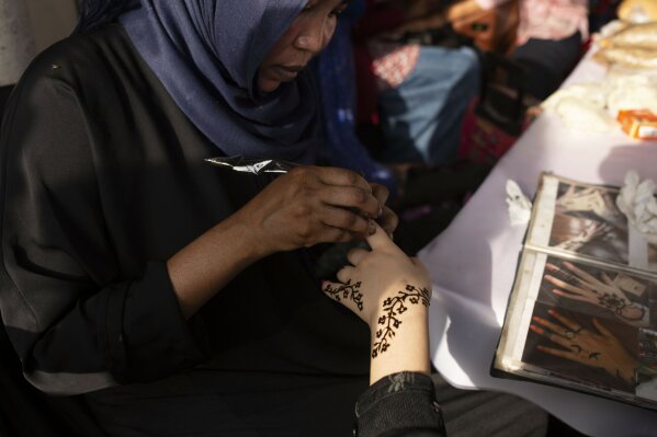 In this June 20, 2019 photo, a Sudanese woman applies henna to a Yemeni girl's hand during an event marking the U.N.'s International Refugee Day, in Cairo, Egypt. The Egyptian capital is home to hundreds of thousands of sub-Saharan African migrants, many who have fled deadly violence or dire poverty at home. But on the streets of Cairo, they face new dangers - harassment, abuse, and sometimes rape. (AP Photo/Maya Alleruzzo)