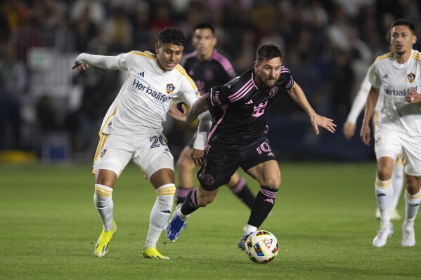 CORRECTS TO SUNDAY NOT SATURDAY - Inter Miami forward Lionel Messi (10) dribbles the ball past Los Angeles Galaxy midfielder Edwin Cerrillo (20) during the first half of an MLS soccer match, Sunday, Feb. 25, 2024, in Carson, Calif. (AP Photo/Kyusung Gong)