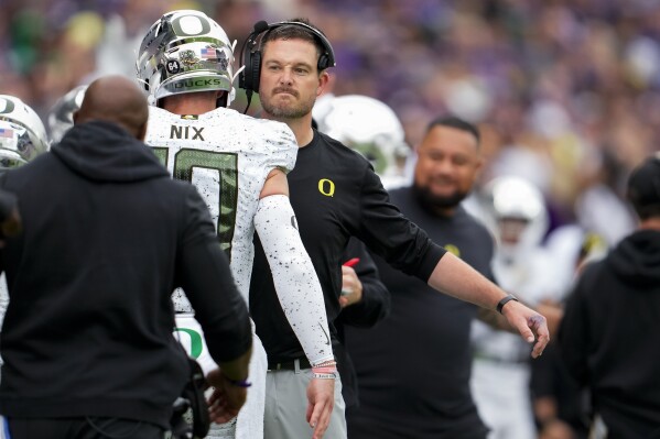 Oregon quarterback Bo Nix is greeted by head coach Dan Lanning during the first half of an NCAA college football game against Washington, Saturday, Oct. 14, 2023, in Seattle. (AP Photo/Lindsey Wasson)