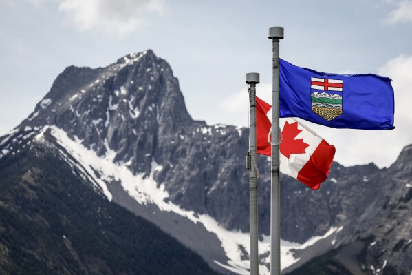 A Canada flag, left, and an Alberta flag flap in the breeze with Wedge Mountain in the background at the site of the G7 Leaders meeting in Kananaskis, Alberta, June 2, 2025. (Jeff McIntosh/The Canadian Press via AP, file)