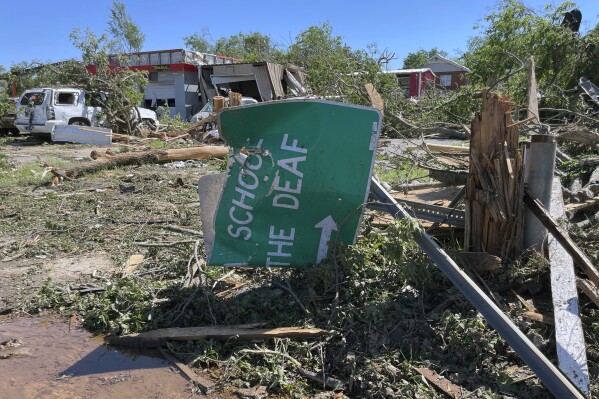 A sign for the Oklahoma School for the Deaf, lies crumpled and twisted near downtown Sulphur, Oklahoma, Monday, April 29, 2024. (AP Photo/Graham Brewer)
