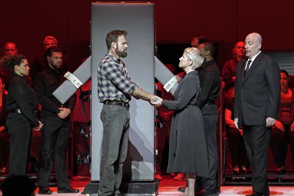 This image released by the Metropolitan Opera shows Ryan McKinny as Joseph De Rocher, foreground left, Joyce DiDonato as Sister Helen Prejean, foreground center, and Raymond Aceto as George Benton in Jake Heggie's 