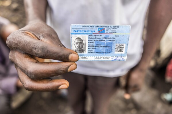 Elisha Manishimwe holds his voter's card in the Kanyaruchinya displaced camp outside Goma, eastern Democratic Republic of the Congo, Saturday, Dec. 9, 2023. As Congo prepares to hold elections on Dec. 20, a record 6.9 million people are internally displaced across the vast Central African nation, according to the United Nations. (AP Photo/Moses Sawasawa)