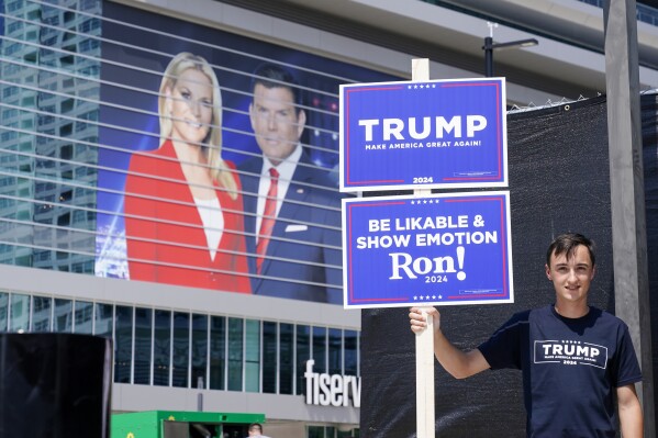 A former president Donald Trump supporter stands near the Fiserv Forum as set up continues for the upcoming Republican presidential debate Tuesday, Aug. 22, 2023, in Milwaukee. (AP Photo/Morry Gash)