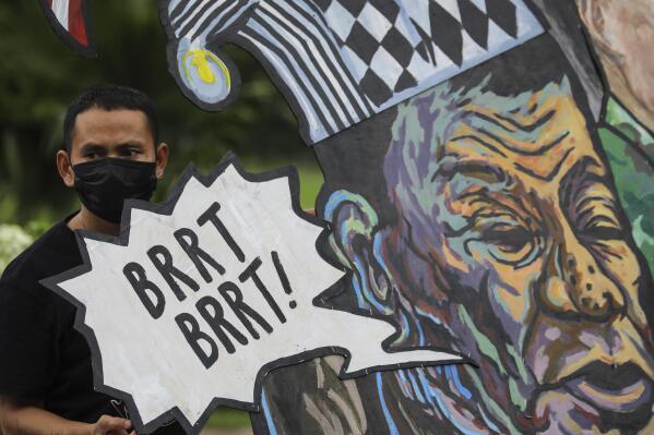 A protester stands beside a caricature of Philippine President Rodrigo Duterte before marching towards the House of Representatives where he is set to deliver his final State of the Nation Address in Quezon city, Philippines on Monday, July 26, 2021. Duterte is winding down his six-year term amid a raging pandemic and a battered economy. (AP Photo/Gerard Carreon)