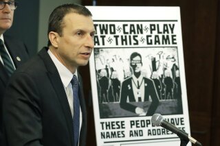 FILE - In this Feb. 26, 2020, file photo, Raymond Duda, FBI Special Agent in Charge in Seattle, speaks as he stands next to a poster that was mailed earlier in the year to the home of Chris Ingalls, an investigative reporter with KING-TV during a news conference in Seattle. A federal judge declined to impose prison time Wednesday, March 31, 2021, on a former member of a neo-Nazi ring that made threats against journalists, finding that the 21-year-old, who concealed his transgender identity from his co-conspirators, had already suffered enough in his young life. (AP Photo/Ted S. Warren, File)