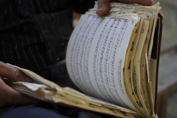 Isaac Green, 34, flips through his personal copy of "The Sacred Harp," a shape-note hymnal linked to a more than 180-year-old American folk singing tradition, at Holly Springs Primitive Baptist Church in Bremen, Ga., on Sunday, March 23, 2025. The 1991 edition has undergone a multi-year revision process conducted by a nine-member committee and will be released by the Sacred Harp Publishing Company in September. (AP Photo/Jessie Wardarski)