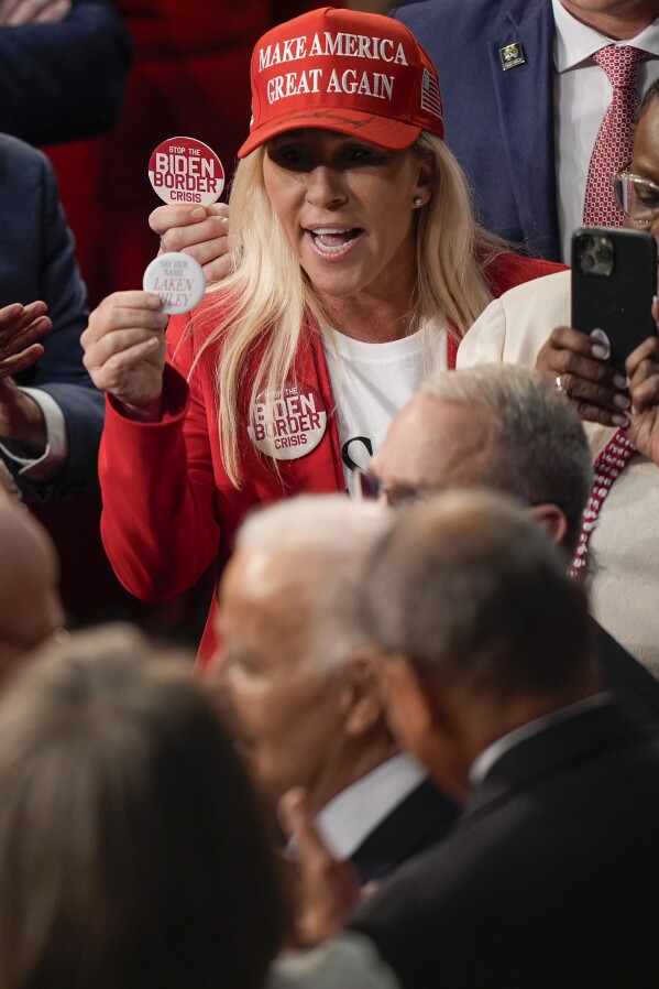 Rep. Marjorie Taylor Greene, R-Ga., top, holding up a Laken Riley button to give to President Joe Biden, bottom before the State of the Union address on Capitol Hill, Thursday, March 7, 2024, in Washington. (AP Photo/Mark Schiefelbein)