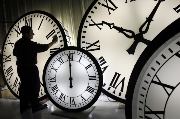 FILE - Electric Time Co. employee Walter Rodriguez cleans the face of an 84-inch Wegman clock at the plant in Medfield, Mass. Thursday, Oct. 30, 2008. Once again, most Americans will set their clocks forward by one hour this weekend, losing perhaps a bit of sleep but gaining more glorious sunlight in the evenings as the days warm into summer. There's been plenty of debate over the practice but about 70 countries — about 40 percent of those across the globe — currently use what Americans call daylight saving time. (AP Photo/Elise Amendola, File)