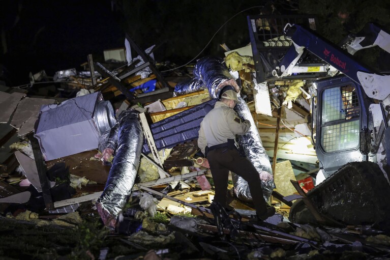 Um policial da patrulha rodoviária estadual de Oklahoma procura danos causados ​​​​por tempestades em Barnstall, Oklahoma, terça-feira, 7 de maio de 2024.  (Mike Simons/Tulsa World via AP)