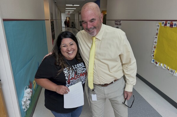 Superintendent Lee White shares a hug with teacher Vanessa Calderon in the hall of the elementary school in Loving, N.M., on Monday, May 19, 2025. (AP Photo/Susan Montoya Bryan)