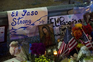 A Virgin Mary painting, flags and flowers adorn a makeshift memorial for the victims of Saturday's mass shooting at a shopping complex in El Paso, Texas, Sunday, Aug. 4, 2019. (AP Photo/Andres Leighton)