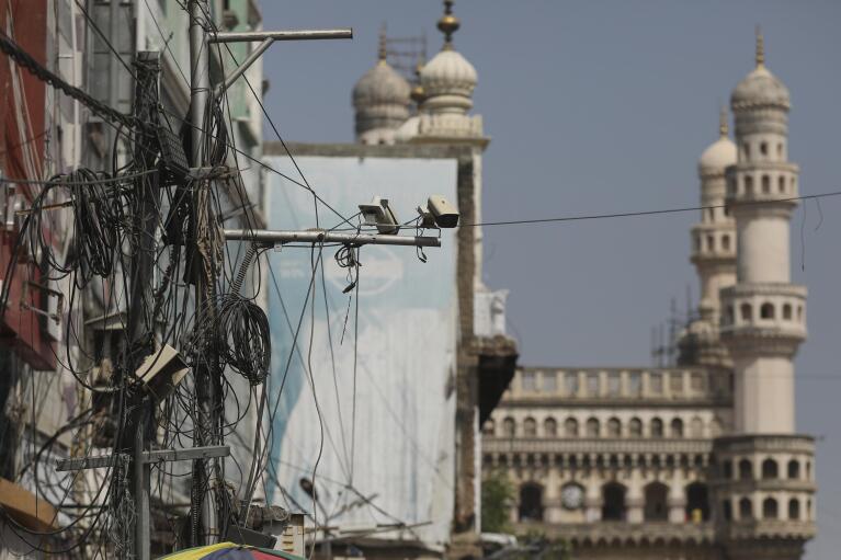 Surveillance cameras are mounted above a street with the landmark Charminar monument seen in the background, in Hyderabad, India, Friday, Jan. 28, 2022. (AP Photo/Mahesh Kumar A.)