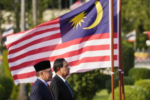 Malaysia's Prime Minister Anwar Ibrahim, left, and Thailand's Prime Minister Prayuth Chan-ocha listen to their national anthems during a welcoming ceremony at the Government House in Bangkok, Thailand, Thursday, Feb. 9, 2023. (AP Photo/Sakchai Lalit)
