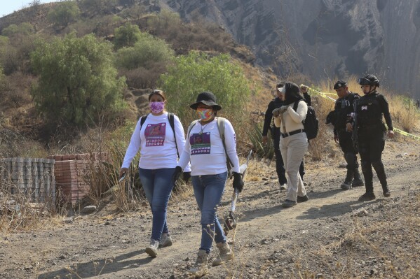 Women carry digging tools at the site where their search team said they found a clandestine crematorium in Tlahuac, on the edge of Mexico City, Wednesday, May 1, 2024. At left is Jacqueline Palmeros who has been searching for her disappeared daughter since 2020 in Mexico City, and at right is María de Jesús Soria whose daughter disappeared in Veracruz in 2016, and whose remains were turned over to her in 2022. (AP Photo/Ginnette Riquelme)