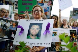 FILE - In this Friday, Aug. 17, 2018, file photo, Christine Gagnon of Southington, Conn., protests with other family and friends who have lost loved ones to OxyContin and opioid overdoses at Purdue Pharma LLP headquarters in Stamford, Conn. Gagnon lost her son Michael 13 months earlier. OxyContin maker Purdue Pharma is expected to file for bankruptcy after settlement talks over the nation’s deadly overdose crisis hit an impasse, attorneys general involved in the talks said Saturday, Sept. 7, 2019, in a message to their counterparts across the country. (AP Photo/Jessica Hill, File)